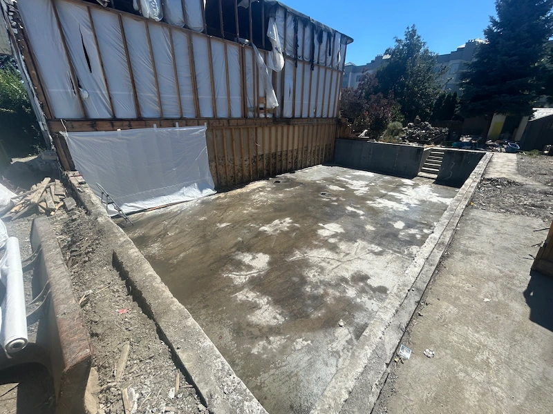 Cleared concrete pad and exposed foundation ready for a basement/addition in Kelowna, BC
