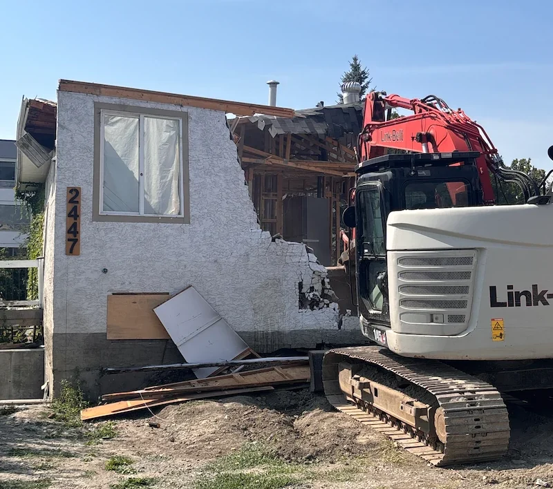 Excavator demolishing a residential house during teardown and site cleanup in kelowna